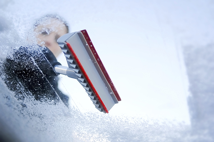 Photo d’une personne grattant de la glace sur le pare-brise de son véhicule.