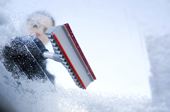 Person scraping ice off the car windshield window