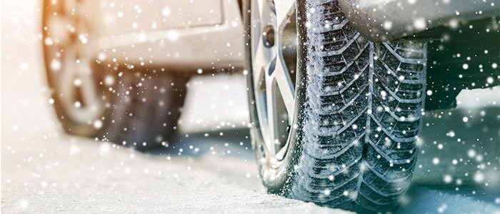 Close up of winter care tire driving in snow