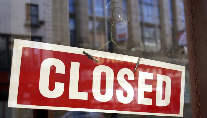 A red and white closed sign in front of a store window