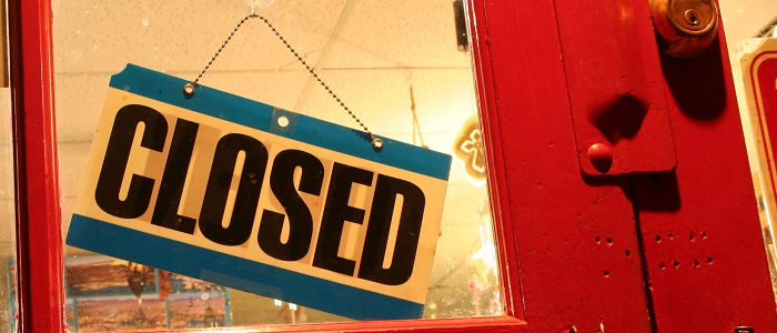 Closed store sign on the glass of a red door