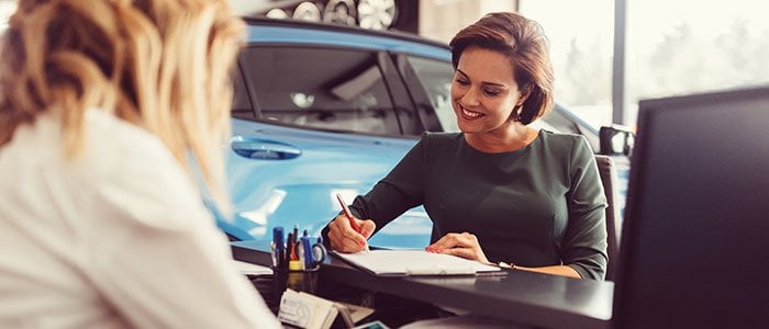 Female auto dealer selling car to client