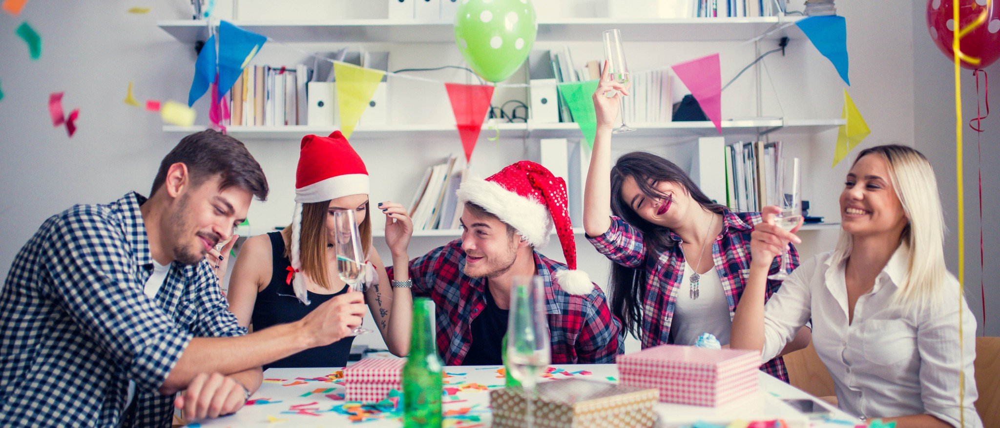 Photo d’employés de bureau souriant et portant un chapeau de père Noël avec un verre à la main.