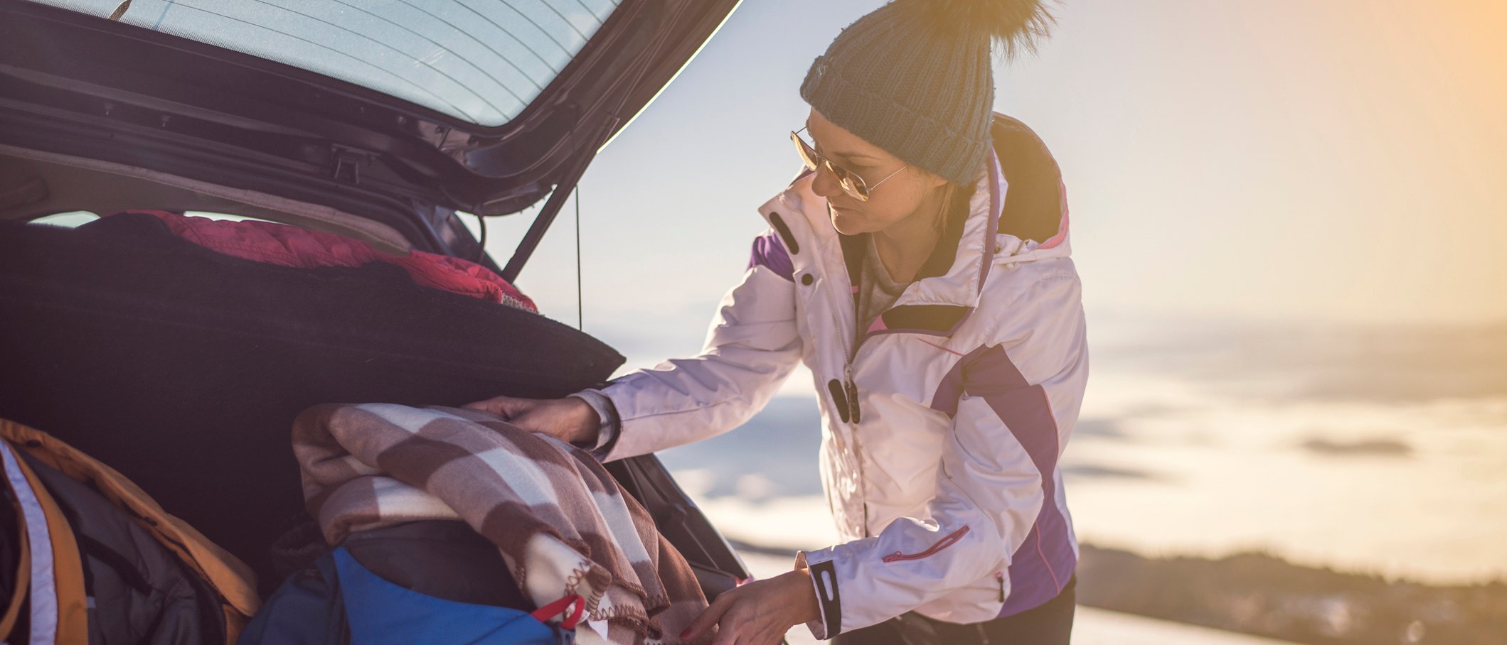 Women taking out an emergency winter safety kit from the back of her car