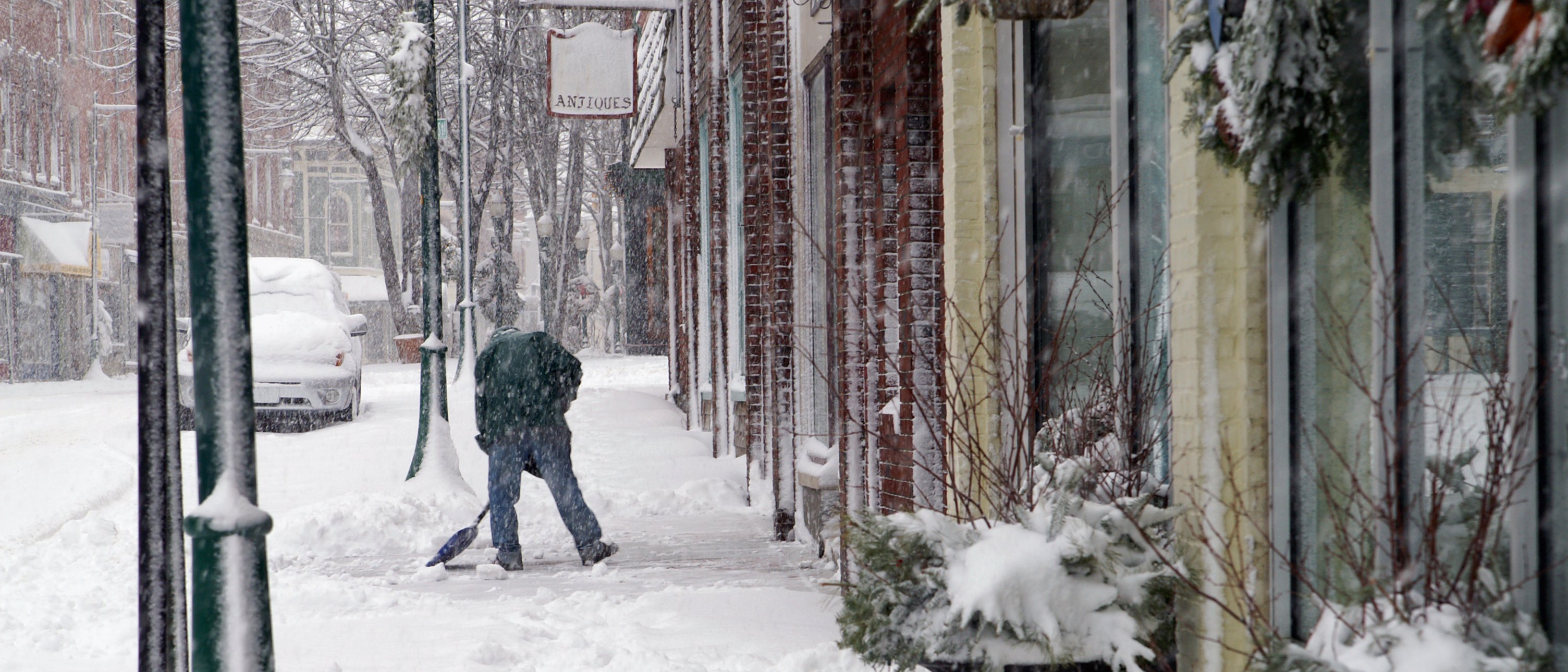 Business owner shovelling snow in front of his shop