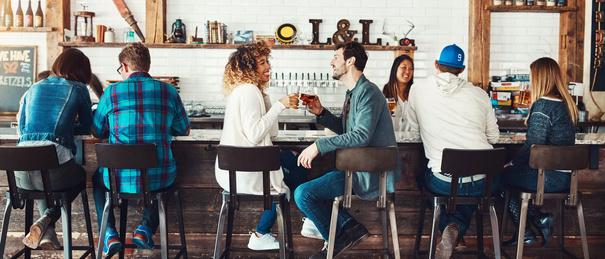 Customers sitting at a bar of a restaurant happily chatting