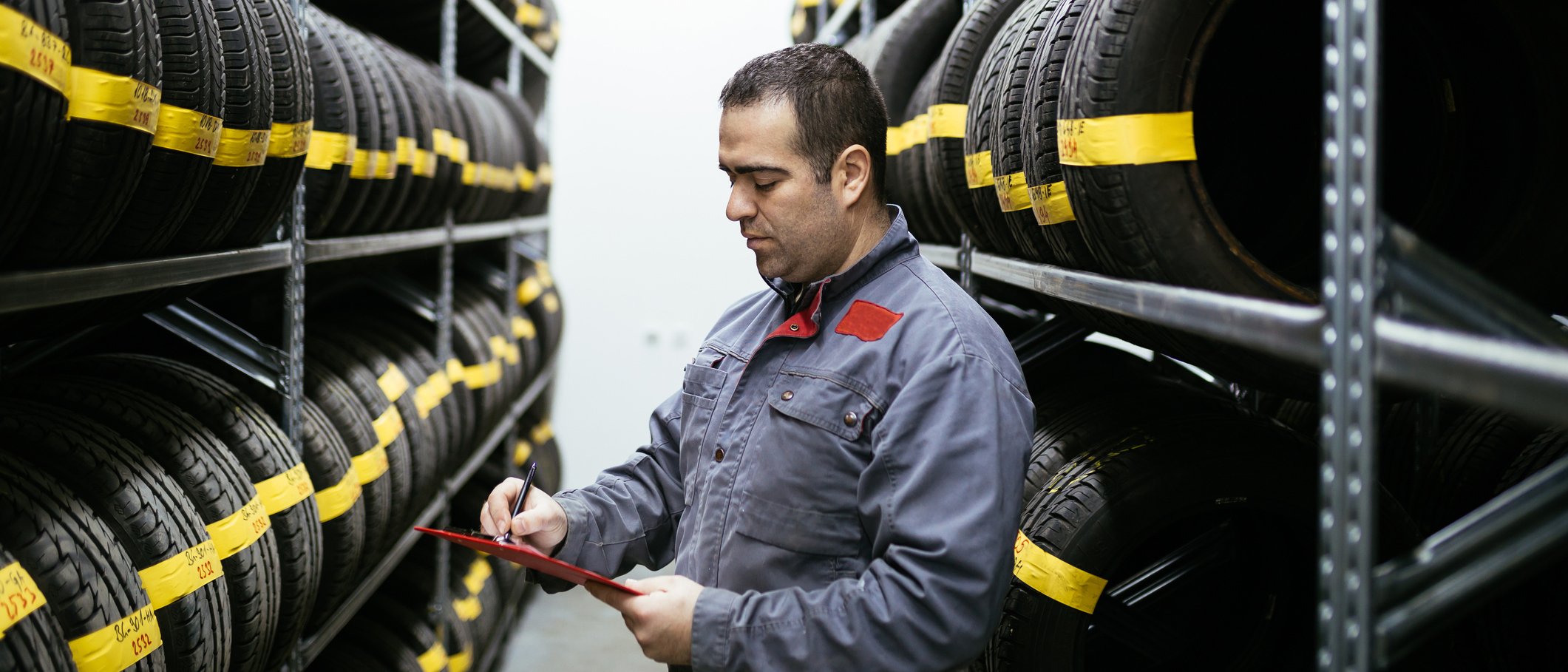 Car mechanic checking to see if tires are stored safely in warehouse