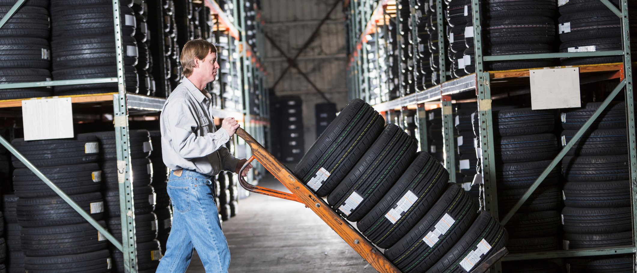 Photo d’un propriétaire d’entreprise entreposant des pneus dans un entrepôt.