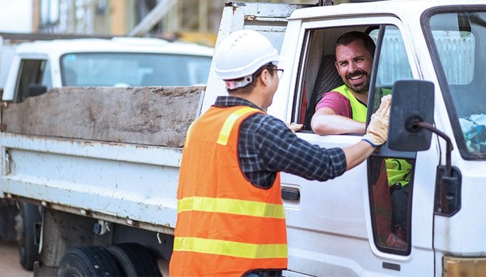 Truck driver happily conversing with construction work on site