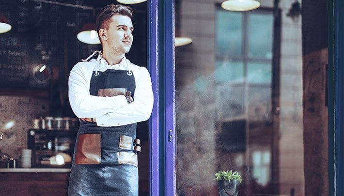 Male business owner standing in front of his shop. 