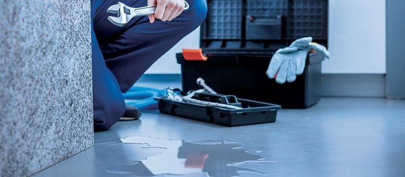 Plumber holding a wrench with their tool box on the side 