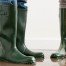Photo rapprochée de deux personnes portant des bottes de pluie en caoutchouc vert.