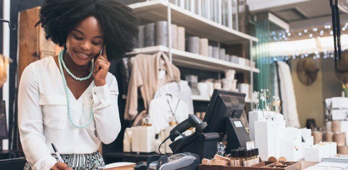 Photo d’une propriétaire d’un magasin de détail parlant au téléphone en souriant.