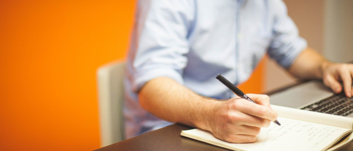 Business man sitting in an orange office working on a business plan