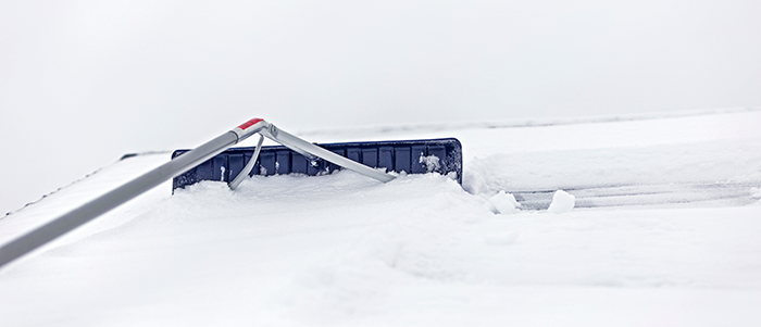 People shovelling snow off a roof.